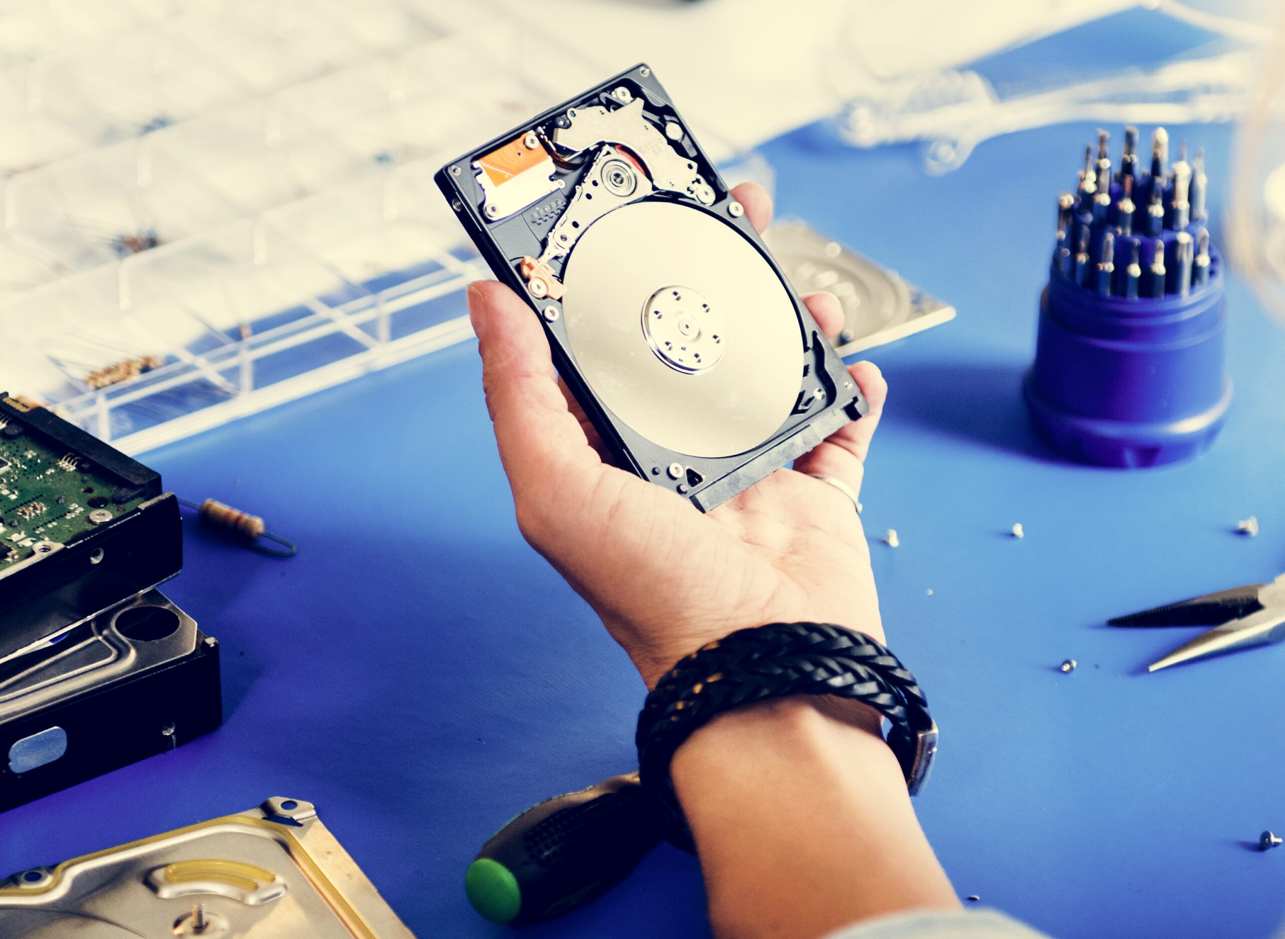 Technicien tenant un disque dur ouvert pour une intervention de récupération de données.